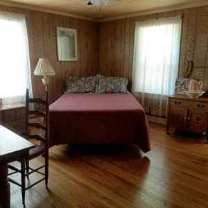 Spacious Garden Room with a queen size bed, table and chairs, desk, rocker and TV hutch.