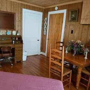 Spacious Garden Room with a queen size bed, table and chairs, desk, rocker and TV hutch.