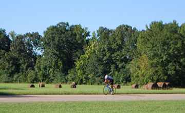 Bicyclist riding past Bear Creek Mound.